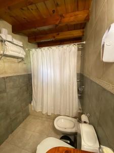 ein Badezimmer mit einem weißen Duschvorhang und einem WC in der Unterkunft Cabañas Rukayen in Villa La Angostura