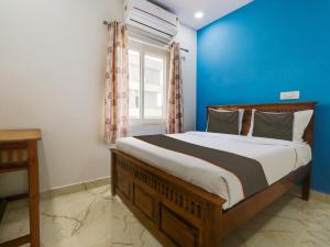 a bedroom with a large bed with a blue wall at Collection O Hotel SR Grand in Bībīnagar