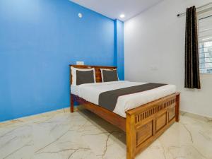 a bedroom with a bed with a blue wall at Collection O Hotel SR Grand in Bībīnagar