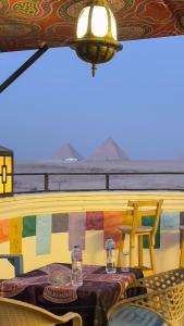 a table with glasses and a chair on a balcony at Atlantis Pyramids Inn New in Giza