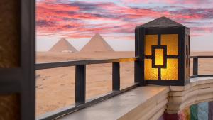 Atlantis Pyramids Inn New في Giza: شمعة على شرفة تطل على الاهرامات