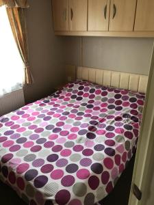 a bed with a polka dot blanket on it at Southview cedar bank 6 in Skegness +2 photos