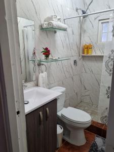 een witte badkamer met een toilet en een wastafel bij Villa Helena in Los Altos de Cerro Azul
