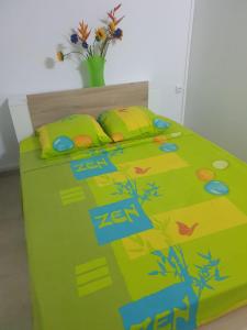Bett mit grüner Bettdecke und Kissen in der Unterkunft A ka lé Mich in Sainte-Rose