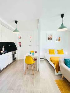 ein weißes Schlafzimmer mit einem Bett und einem gelben Stuhl in der Unterkunft Domus da Ria in Aveiro
