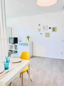 a white dining room with a table and a yellow chair at Domus da Ria in Aveiro