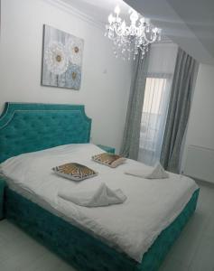 een slaapkamer met een groen bed met 2 kussens erop bij PAONI Apartment by Solid Residence Butoaie Mamaia in Mamaia