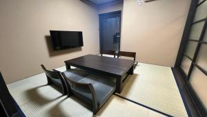 uma sala de jantar com uma mesa e cadeiras e uma televisão em Tsumugi Horikawarokkaku em Quioto
