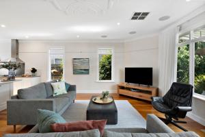 a living room with a couch and a tv at Essendon Allambee Haven 4BR in Melbourne
