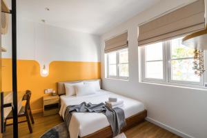 a bedroom with a bed and a desk and two windows at Tròn Beach Villa- NovaWorld Phan Thiet in Phan Thiet