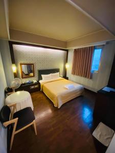 ein Hotelzimmer mit einem Bett und einem Tisch in der Unterkunft Hotel Lee-Chan in Taipeh