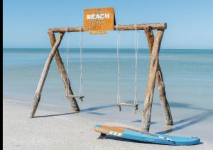 - une balançoire sur la plage avec une planche de surf sur la plage dans l'établissement Tótem Beach Club, à Celestún