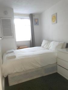 um quarto com uma grande cama branca e uma janela em Cozy One Bed Apartment Near Purley Station em Purley