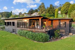a house with a large deck on a lawn at Sanctuaire, Southern Highlands in Mittagong