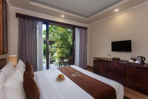 The Mudru Resort by Pramana Villas في أوبود: غرفة نوم بسرير كبير وتلفزيون