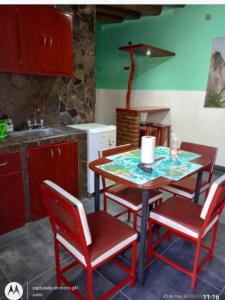 een keuken met een tafel met rode stoelen en een wastafel bij Flor de los andes in Fiambala