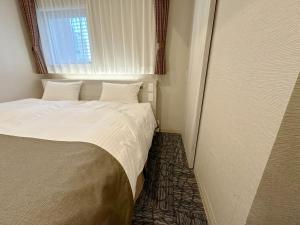 a bed in a small room with a window at S.Training Center Hotel Osaka in Osaka