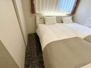 two beds in a small room with a window at S.Training Center Hotel Osaka in Osaka