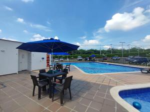 un patio con tavolo e sedie accanto alla piscina di CALI Acogedor y Nuevo apartamento cerca de Jardin plaza, con piscina, parqueadero y aire acondicionado a Cali