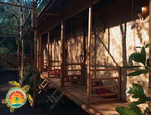 eine hölzerne Veranda eines Gebäudes mit einem Schild darauf in der Unterkunft Uncle Hippie's Dream in Gili Meno