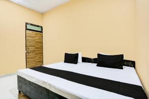 a bedroom with a large white bed with black pillows at OYO Hotel H.R in Garhi Harsāru