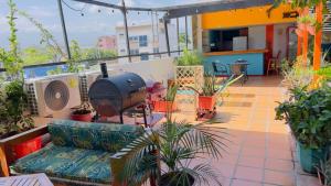 a patio with a couch and a grill on a balcony at Aparta Hotel Bacano Historico in Santa Marta
