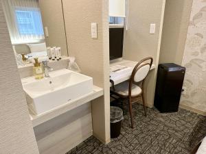 a bathroom with a sink and a desk with a mirror at S.Training Center Hotel Osaka in Osaka