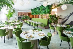 restauracja z białymi stołami i zielonymi krzesłami w obiekcie Capri by Fraser China Square, Singapore w Singapurze