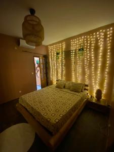 - une chambre dotée d'un lit avec des lumières sur le mur dans l'établissement Keur royal, à Dakar