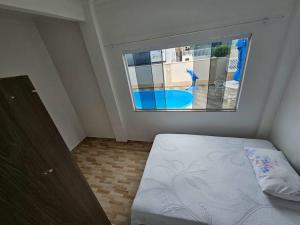 a bedroom with a bed and a large window at Casa de praia com piscina TOP in Paraty