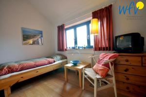 a bedroom with a bed and a tv and a chair at Ferienhaus Friesenblick Ferienwohnung 1 in Wangerooge