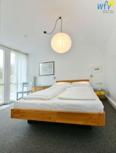 ein Schlafzimmer mit einem großen Bett und einer Lampe in der Unterkunft Haus Skagen Ferienhaus Skagen Wangerooge in Wangerooge