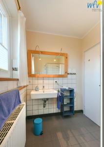 ein Bad mit einem Waschbecken und einem Spiegel in der Unterkunft Haus Skagen Ferienhaus Skagen Wangerooge in Wangerooge