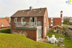 ein Backsteinhaus mit einem Balkon und einer Terrasse in der Unterkunft Haus Skagen Ferienhaus Skagen Wangerooge in Wangerooge