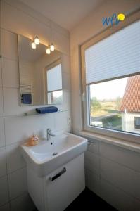 Un baño con lavabo, espejo y ventana. en Ferienhaus Wangehüs, en Wangerooge