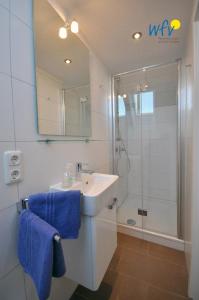 y baño con lavabo y ducha con toallas azules. en Ferienhaus Wangehüs, en Wangerooge 20 fotos más