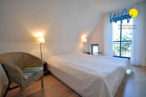a bedroom with a bed and a chair and a window at Ferienhaus Friesenblick Ferienwohnung 2 in Wangerooge