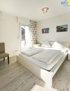 a large white bed in a room with a window at Fischerhus Ferienhaus Fischerhus Wangerooge in Wangerooge