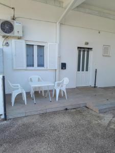 d'une terrasse avec des chaises blanches, une table et une porte. dans l'établissement Apartments with a parking space Njivice, Krk - 22769, à Njivice