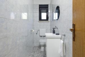 a white bathroom with a toilet and a sink at Holiday house with a parking space Drnis, Zagora - 22772 in Drniš +4 photos