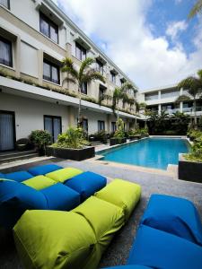 a hotel with a pool and some blue and green beds at ILLIRA Lite Praya Lombok in Praya