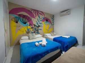 嘎林海斯港Pousada Porto Sol的房间里有两张床，墙上有一幅壁画
