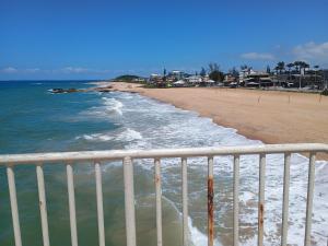 a view of a beach with a white fence at Triplex 3 quartos a 100 metros de Costa Azul in Rio das Ostras