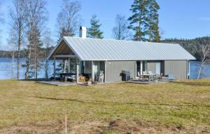 una pequeña casa en la cima de una colina junto a un lago en Gorgeous Home In Gustavsfors With Kitchen en Gustavsfors