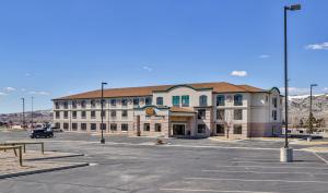 a large building in a parking lot with mountains in the background at Sweetwater Lodge - Rock Springs - Green River in Rock Springs