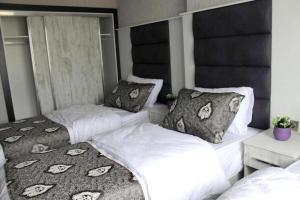two beds in a bedroom with white sheets and pillows at Kaya Home Apart Otel in Trabzon