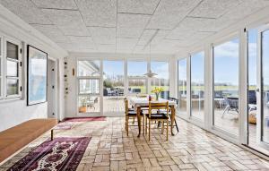 a dining room with a table and chairs and windows at 5 Bedroom Gorgeous Home In Bjørnø in Bjerne