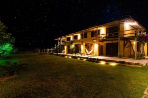 a house with lights in the yard at night at Kahuma in Imbituba