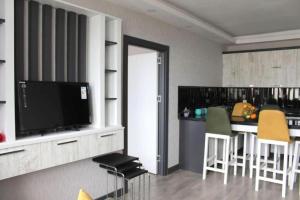 a kitchen with a bar with chairs and a television at Kaya Home Apart Otel in Trabzon
