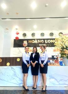un grupo de tres mujeres frente a un cartel en Hoang Long Hotel Phan Thiết, en Phan Thiet
